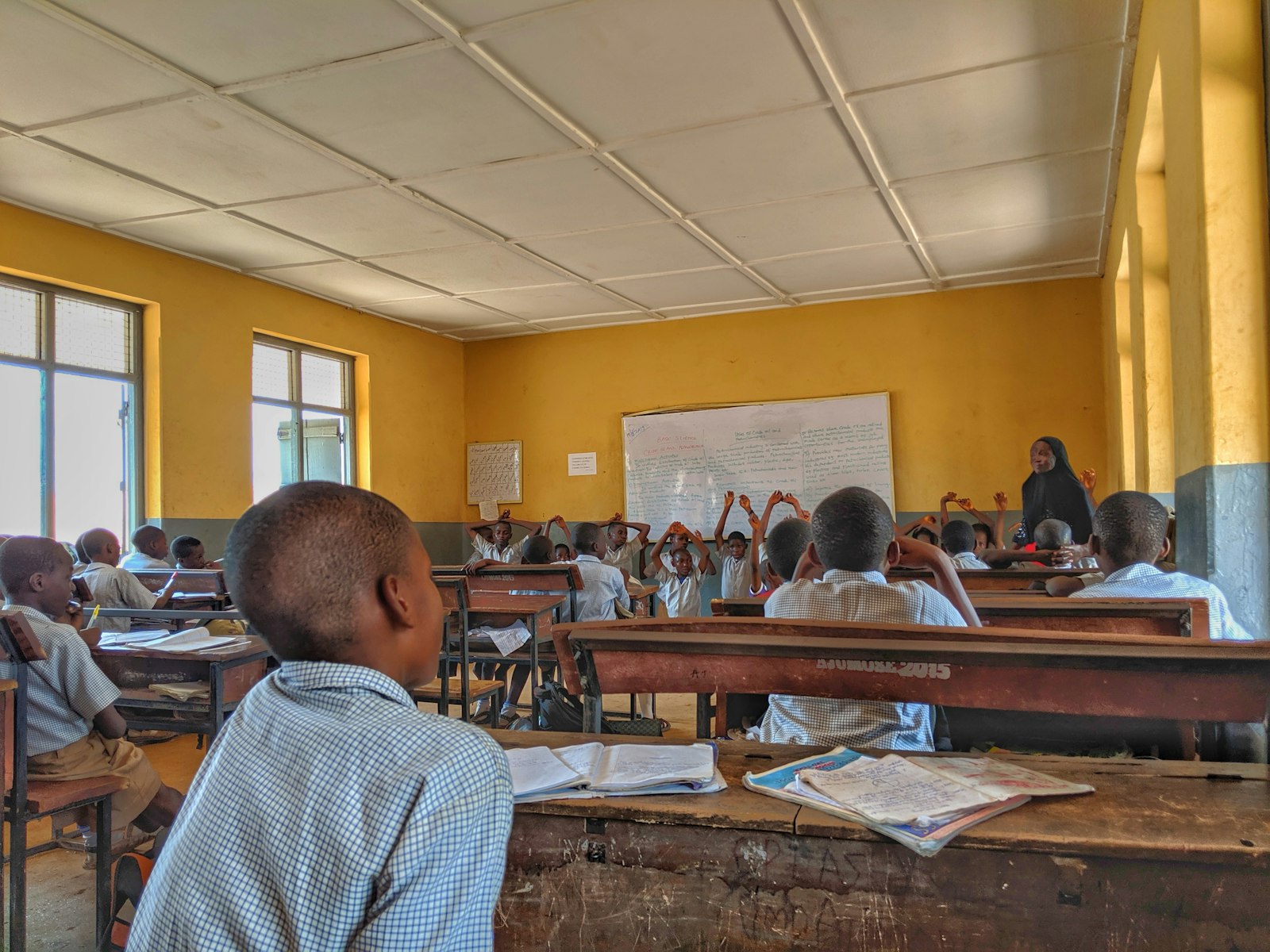 Une enseignante fait cours dans une salle de classe colorée, entourée de ses élèves